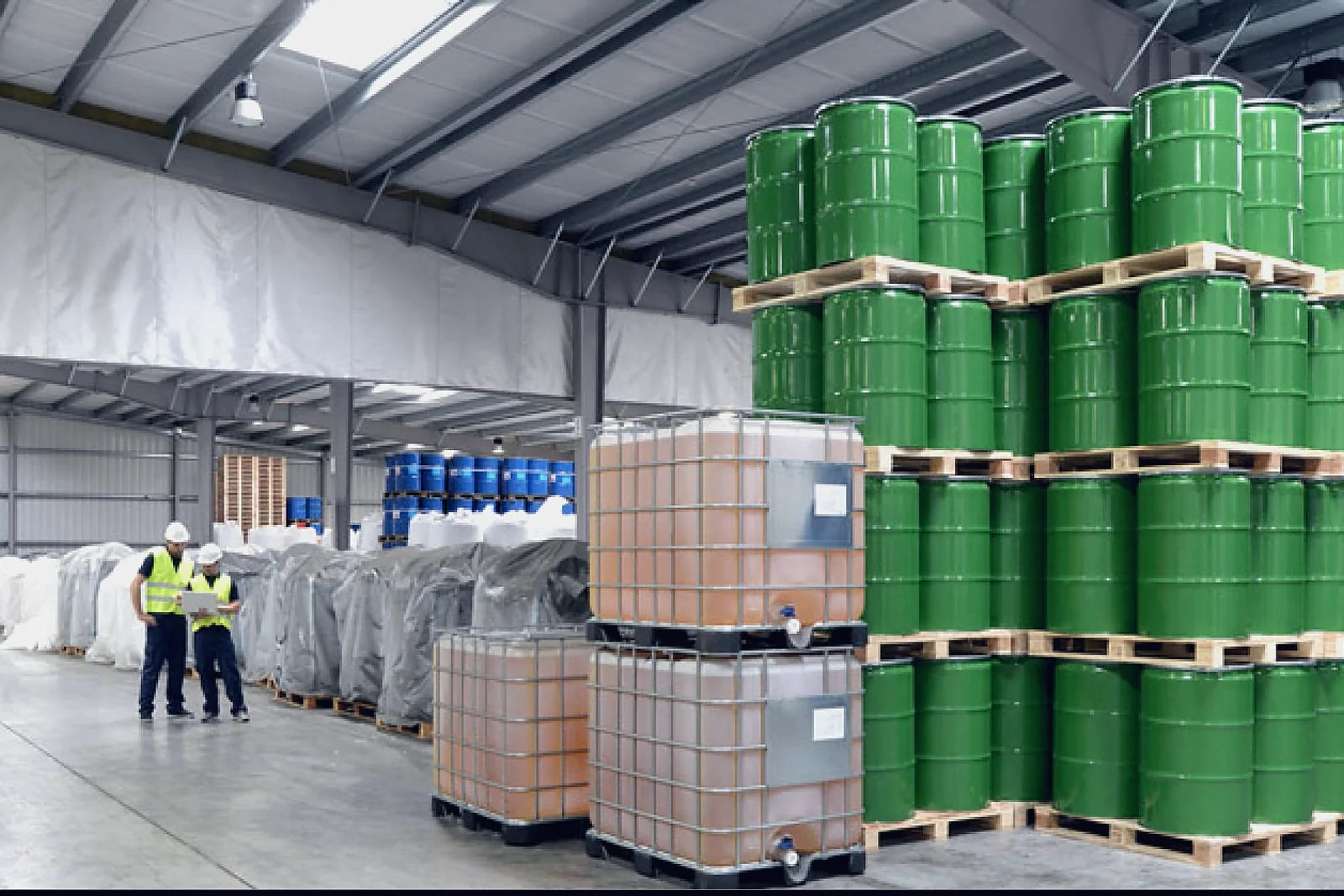 Chemical store with drums, IBC totes and an operator in high-visibility clothing