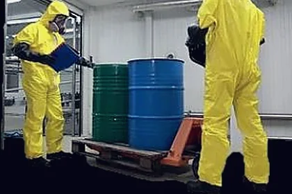Operators in chemical protective suits handling drums